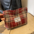Detail einer rotbraun karierten Tweed-Kosmetiktasche mit Vintage-Webetikett und Textur - Rot