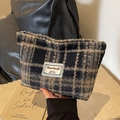 Nahaufnahme der Retro-Kosmetiktasche mit Karomuster und gewebter Stoffstruktur - Schwarz