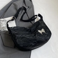Sac hobo noir plissé avec emblème papillon argenté sur fond de costume gris - Noir