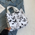 Witte canvas shopper met zwarte vlinderprint op een denim jasje achtergrond - Klein Gebroken Wit