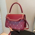 Borsa rossa trapuntata con ricami a cuore dorati e manico superiore su sfondo neutro - Rosso