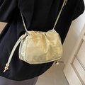 Bolso bandolera beige fruncido con cadena dorada sobre ropa oscura - Verde