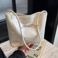 Elegant cream white shoulder bag with bow detail and slim straps, handheld lifestyle view - White