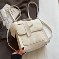 Elegante bolso de mano blanco crema con lazo en cuero charol sobre fondo de blazer - Blanco