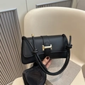 Black leather underarm bag featuring a signature gold H-buckle and knotted strap - Black