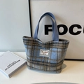 Tote bag en laine à carreaux bleu et gris avec étiquette de marque sur bureau minimaliste - Petit Bleu Sans Pendentif