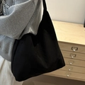 Minimalist large black tote bag for women shown with a stylish casual outfit - Black