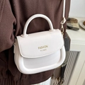 Creamy off-white saddle bag with gold logo and shoulder strap worn by model - White