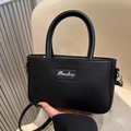 Minimalist black matte leather crossbody bag with silver metal branding and round handle - Black