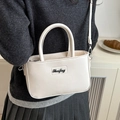 Chic cream white crossbody square bag with top handles and adjustable strap worn by model - Off White