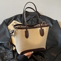 Minimale crème tote bag met bruine handvatten en verstelbare riem op een leren jas - Wit