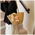 Detailansicht der khakifarbenen gewebten Tasche mit weißer Spitzenschleife und Anhänger - Kaffee + Rosa Blumenanhänger + Band