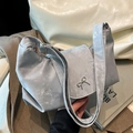 Bolso de hombro plateado metalizado con lazo sobre abrigo marrón y libros de arte - Plateado
