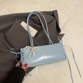 Light blue underarm bag with pearl bow and side ribbons on a grey suit background - Blue + Pearl Bow Charm