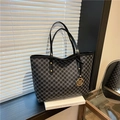 Borsa tote nera con motivo M grigio e ciondolo dorato a M su un tavolino laterale - Nero