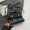 Glossy black vintage square crossbody bag with gold metallic buckles on a grey blazer - No Pendant / Black