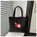 Detailed close-up of nylon tote bag with red apple embroidery on a minimalist setup - Black