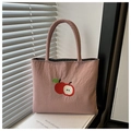 Detailed embroidery of apples on a dust pink nylon handbag near a window - Pink