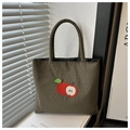 Detail of embroidered apple pattern on dark green nylon bag with soft padded handles - Green