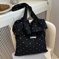 Black floral mesh tote bag with ruffle trim and Magic Pocket label on white chair - Black