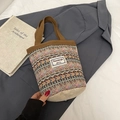 Ethno-Webtasche mit geometrischen Mustern und braunen Griffen auf minimalistischem Hintergrund - Braun