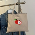 Beige canvas tote bag featuring red apple embroidery in a casual everyday scene - Khaki