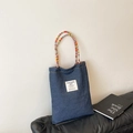Dark blue denim tote bag with colorful handcrafted woven handles and white textile label - Small / Blue