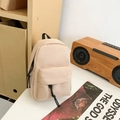 Mini beige canvas rugzak met zwarte ritsen op een rustieke houten achtergrond - Khaki