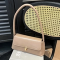 Minimalist beige baguette shoulder bag with gold square buckle on a black rattan chair - Khaki