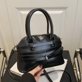 Glossy black crossbody bag featuring decorative straps and silver buckles - Black