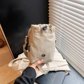 Nylon drawstring crossbody bag in khaki finish with round metal emblem and adjustable strap - Khaki