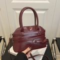 Deep red dome satchel with decorative straps and silver buckles in a stylish lifestyle setting - Red