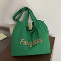 Borsa tote in nylon verde con scritte arancioni e coulisse su superficie in legno - verde scuro