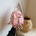 Mini mochila rosa de cuero sintético con lazo grande, vista de mano en estilo lifestyle - Rosa