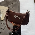 Minimalist dark brown crescent bag with silver bow accent and knotted handle detail - Coffee