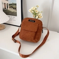 Bolso bandolera de pana marrón con bolsillo frontal sobre una mesa blanca limpia - Marrón