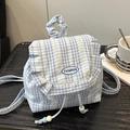 Mochila mini de cuadros azules con ribete de encaje y bordado sobre mesa de madera - Azul