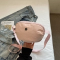 Sac bandoulière en nylon rose texturé avec logo en métal sur fond de style de vie - Rose