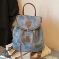 Vintage-Rucksack aus Denim mit braunem Lederbesatz auf einem silbernen Koffer - Blau