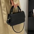 Elegante schwarze Lederhandtasche mit goldenen Metallbeschlägen in modernem Interieur - Schwarz