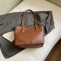 Brown leather tote bag with FASHION embossed logo on a grey blazer, minimalist style - Brown Without Charm