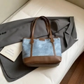 Light blue denim tote bag with brown leather handles and fashion logo in a lifestyle setting - No Pendant / Blue