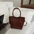 Borsa a secchiello in pelle marrone scuro con scritta FASHION su un divano bianco - Marrone Scuro