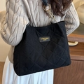 Borsa tote trapuntata nera con catena dorata indossata da una modella di profilo - Nero