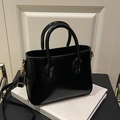 Glänzende schwarze Handtasche mit goldenen Details und verstellbarem Riemen in Variantenansicht - Schwarz