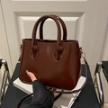 Dunkelbraune glänzende Lederhandtasche mit goldenen Beschlägen und Tragegriffen - Kaffeebraun