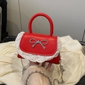 Mini borsa rossa con bordo in pizzo bianco e fiocco argentato su fondo in tessuto crema - Rosso