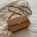 Chic caramel brown baguette bag with golden metal buckle on neutral aesthetic background - Khaki