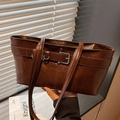 Borsa tote retrò marrone scuro con fibbia e trama in pelle vintage in una luce soffusa - Marrone