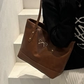 Bolso tote marrón con lazo metálico plateado y remaches, llevado por una modelo - Marrón
